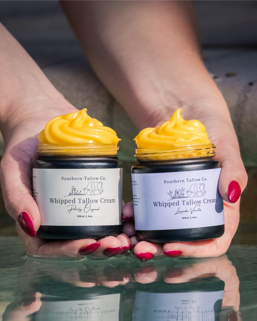 Two hands holding jars of whipped cream with a blurred background